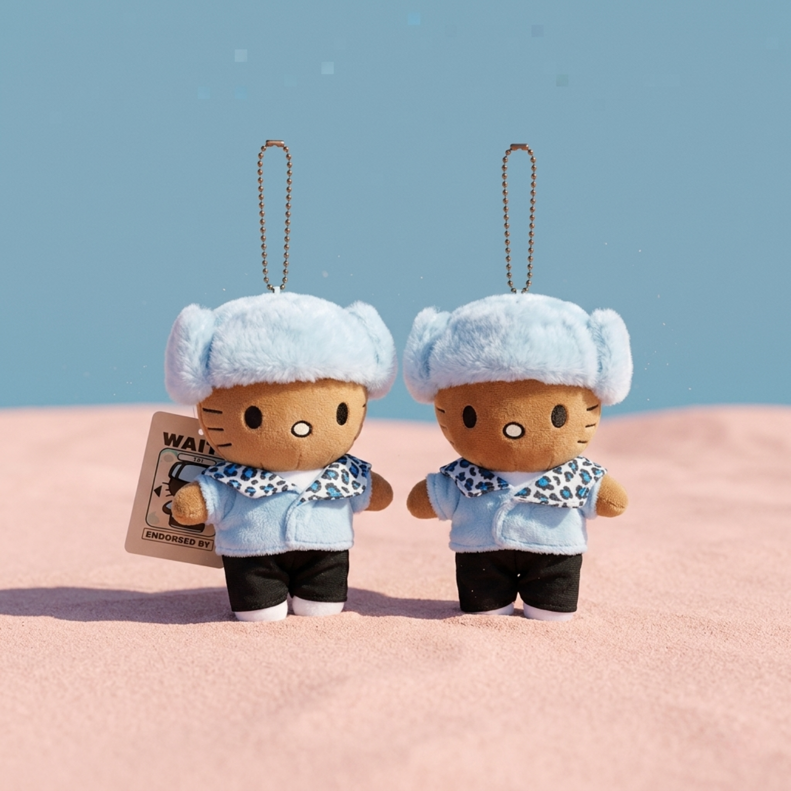 Two plush keychains with a blue sky and pink ground background